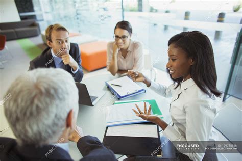 Business people talking at table in office building — women, partners ...