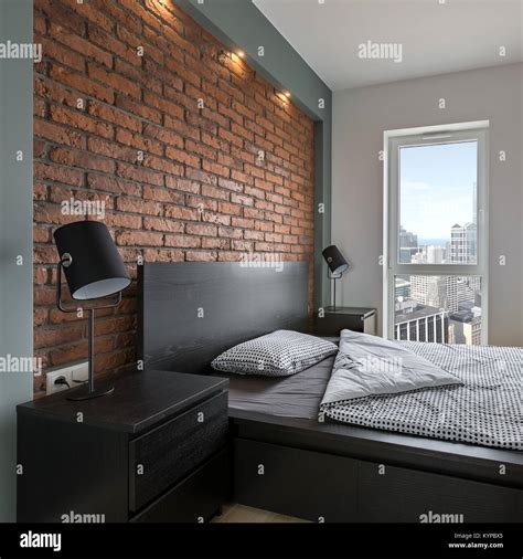 Industrial style bedroom with red, brick wall and double bed Stock Photo - Alamy