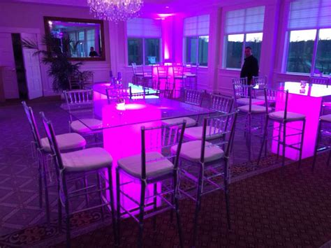 a room filled with white bar stools and purple lighting