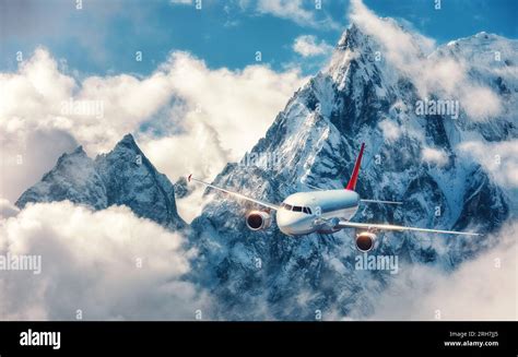 Airplane is flying over clouds against mountains Stock Photo - Alamy