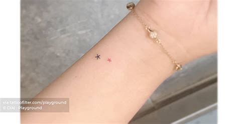 Micro stars tattooed on the wrist, minimalistic style.