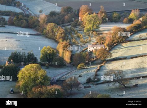 House and farmland in the valley of Downham Hill from Uley Bury on a cold frosty autumn morning ...