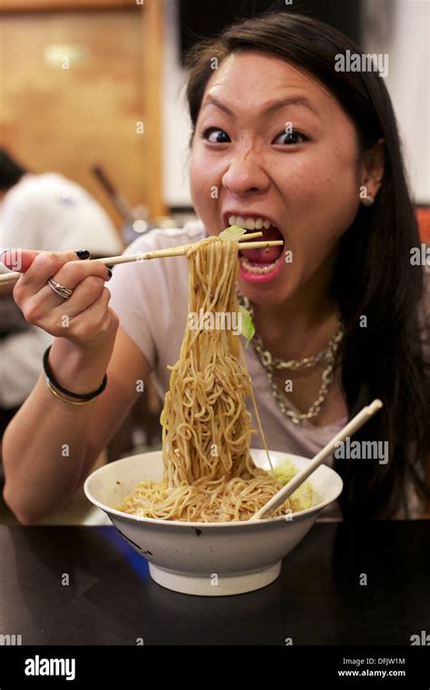 Young Asian girl eating Chinese noodle dish at a restaurant in ...