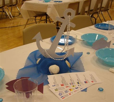 the table is set with blue and white plates, silverware, and an anchor ...