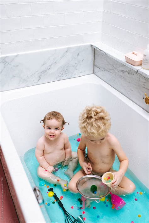 "Sensory Bath Time Play For A Baby Girl And Toddler Boy With Colorful Pompons And Blue Water" by ...