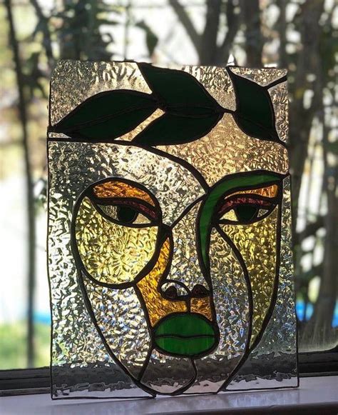 a close up of a stained glass window with leaves on it's head and face