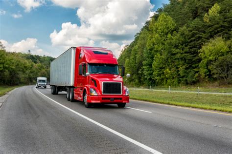 Red Tractor Trailer On A Roadway Through Trees Stock Photo - Download Image Now - iStock