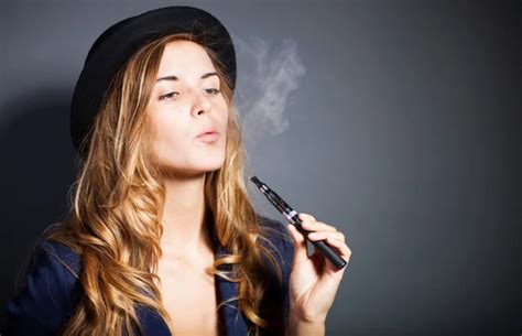 Elegant woman smoking e-cigarette with smoke wearing suit and hat Stock ...