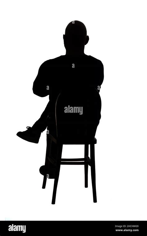 rear view of the silhouette of a man sitting on chair with casual ...