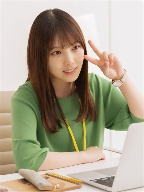 a woman sitting in front of a laptop computer making the peace sign with her hand