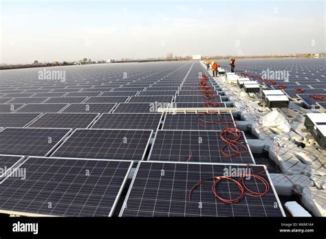 --FILE--Chinese workers install solar panels at a photovoltaic power ...