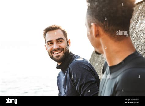 Two attractive smiling young healthy sportsmen outdoors at the beach, talking Stock Photo - Alamy