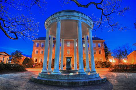 a gazebo lit up at night in front of a large building with columns and pillars