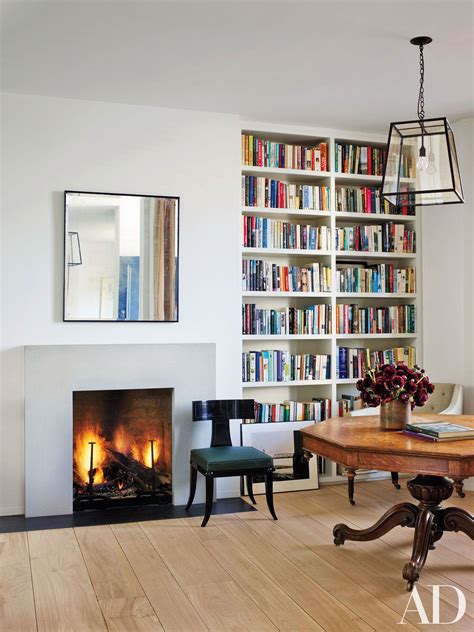 The library of a renovated London rowhouse features built-in bookcases and a minimal fireplace ...