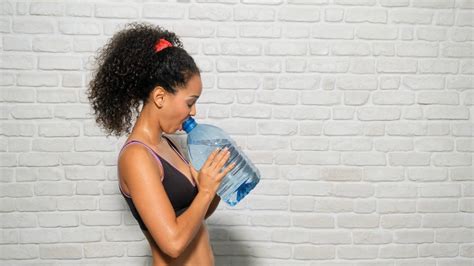 Young people, health and fitness. Portrait of tired african american woman drinking water bottle ...