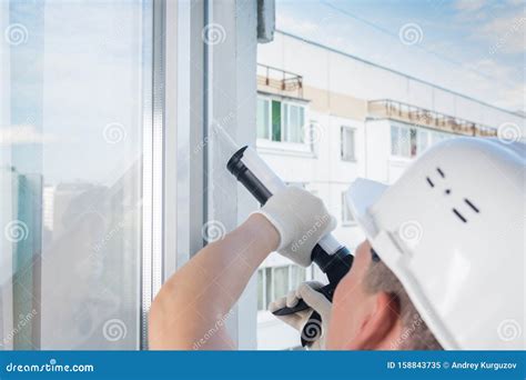 A Window Installation Worker Seals A Plastic Window Frame With A ...