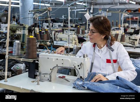 Working Woman hands in textile factory sewing on industrial sewing machine. Industrial ...