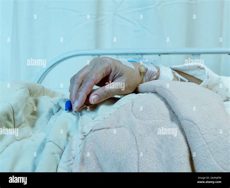 Hand with saline IV drip needle on hospital bed Stock Photo - Alamy