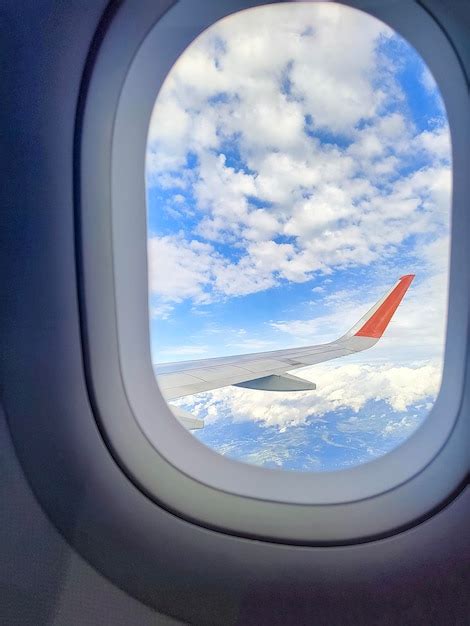 Premium Photo | Blue cloudy sky with the wing of the airplane seen outside the window.