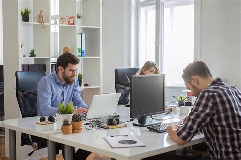 "A Group Of People Sitting At Their Desks Working On The Computers In The Office" by Stocksy ...