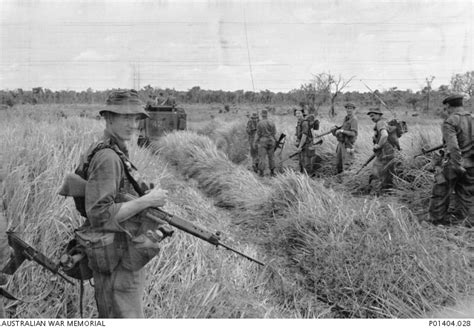 Soldiers of 6th Battalion, The Royal Australian Regiment (6RAR), follow an armoured personnel ...