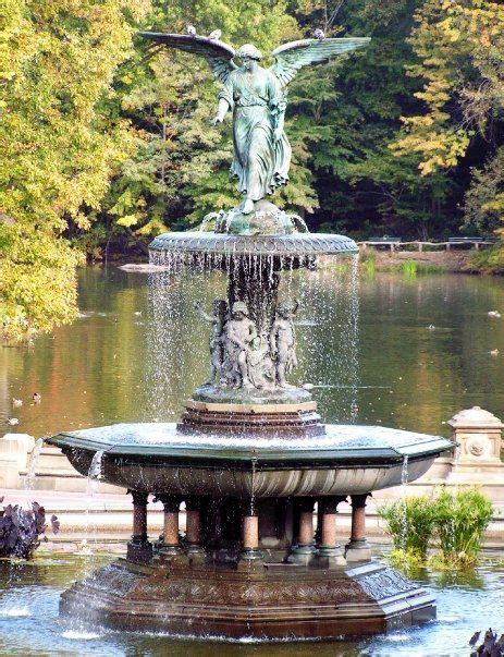 a fountain with an angel statue in the center surrounded by water and trees on either side