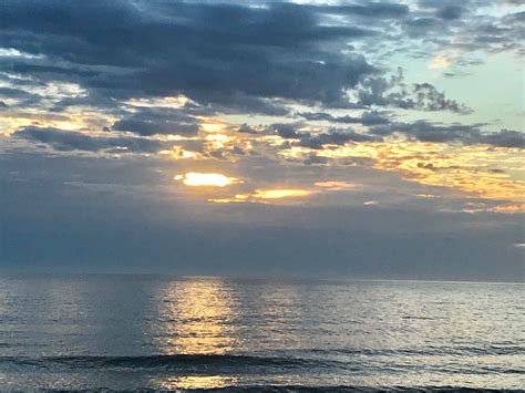 the sun is setting over the ocean with clouds in the sky and some water ...