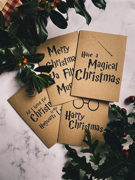 three harry potter christmas cards sitting on top of a table next to holly wreaths