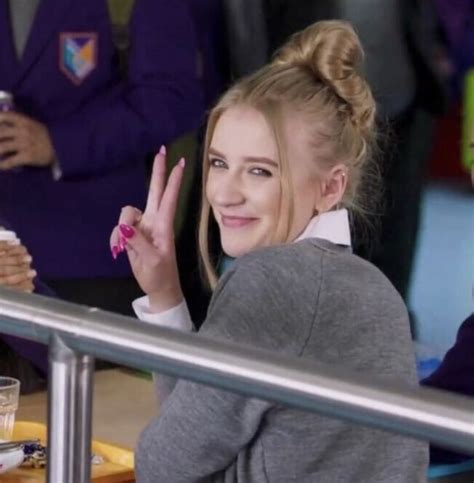 a woman sitting at a table making the peace sign