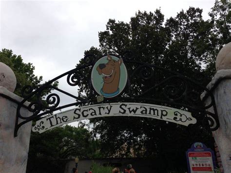 the sign for the scary swamp entrance is posted above an iron gate with a cartoon dog on it