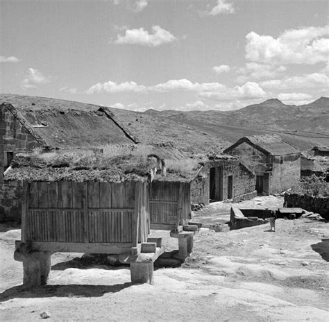 black and white photograph of an old village with mountains in the backgrouds