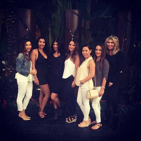 a group of women standing next to each other in front of a plant ...