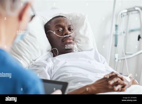 Portrait of African-American man lying in hospital bed and looking at doctor, copy space Stock ...