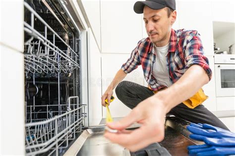 Process of Dishwashing Machine Installation. Young African Service Man Setting Up Dishwasher in ...