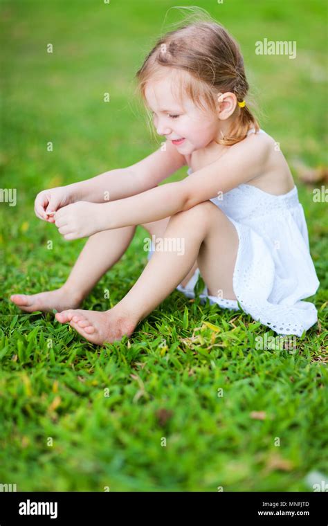 Adorable little girl sitting on a grass Stock Photo - Alamy