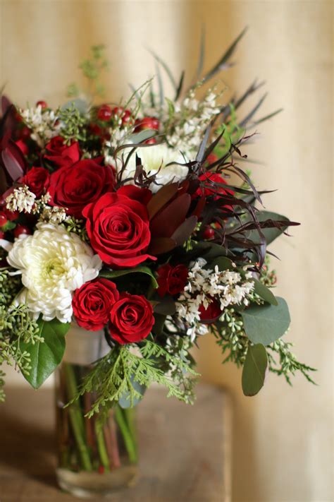 Winter wedding bridal bouquet with red roses, red spray roses, leucadendrum, agonis foliage ...