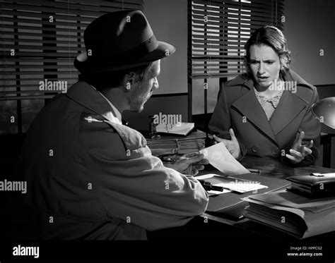 Handsome detective at office desk showing a picture to a young woman, film noir scene Stock ...