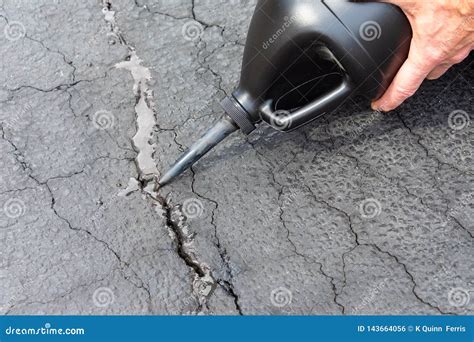 Repairing Cracks in Driveway with Asphalt Crack Filler Stock Photo - Image of homeowner ...