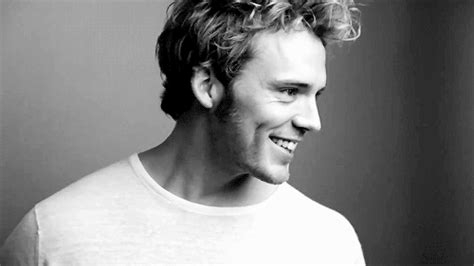 a black and white photo of a young man with curly hair smiling at the camera