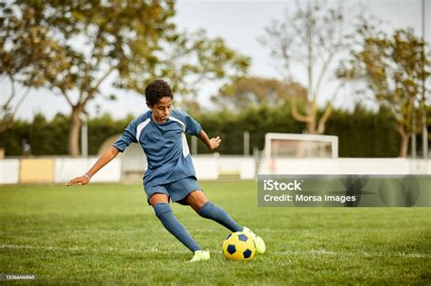 Teenage Boy Kicking Soccer Ball In Field Stock Photo - Download Image ...