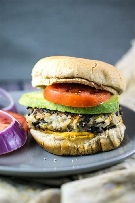 Vegan wild rice burger inside a bun on a plate next to a stack of ...