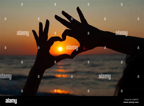 heart Sign with hands against the sunset, sunrise on the sea Stock Photo - Alamy