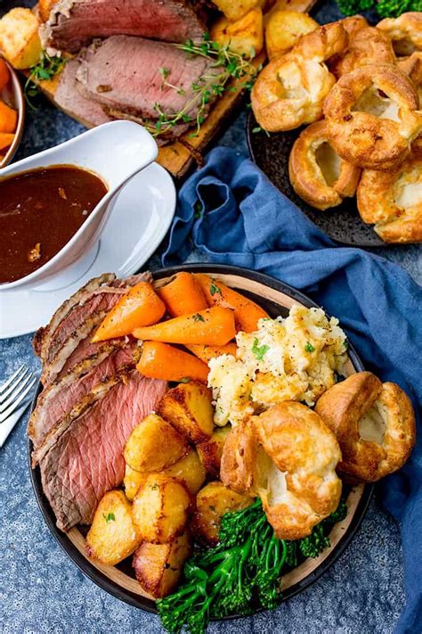 roast beef, potatoes and carrots on a plate with gravy in the background