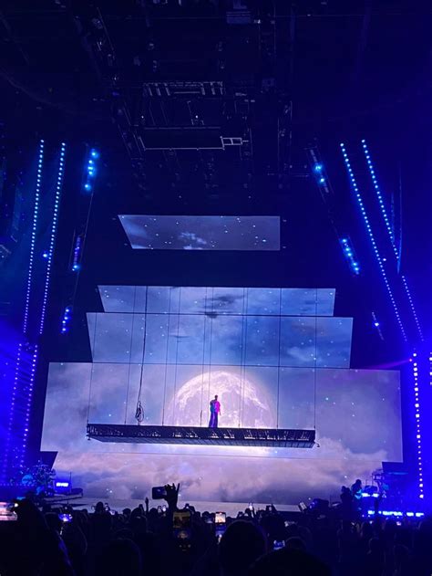 the stage is lit up with blue lights and people are standing on it in front of them