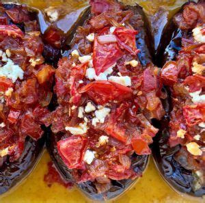 stuffed eggplant with tomatoes and other toppings on a yellow plate, ready to be eaten