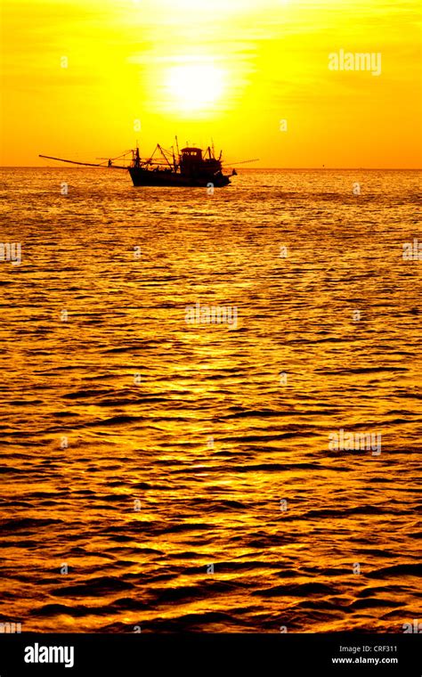 Fishing boat at sunset Stock Photo - Alamy