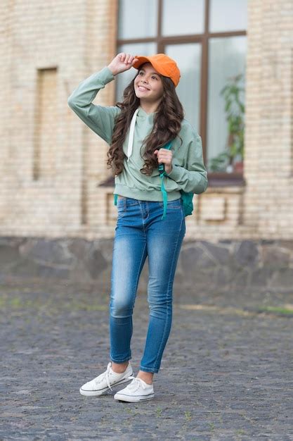 Premium Photo | Stylish little girl fix cap with fashion look wearing casual clothes on urban ...