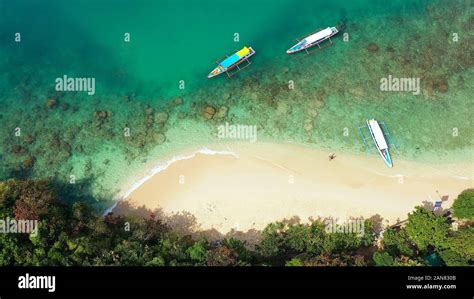 Tropical beach and turquoise water of the lagoon with tourists and boats, view from above ...