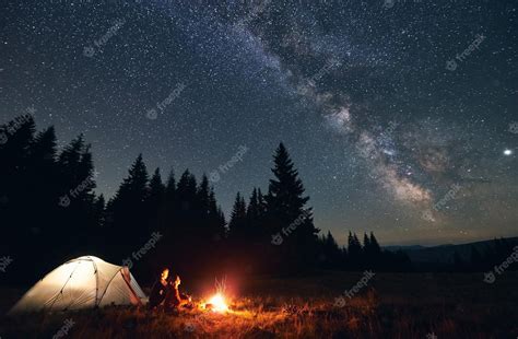 Premium Photo | Couple enjoying starry night sky near campfire