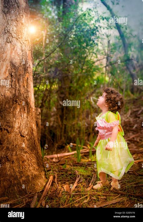 little girl in forest dressed as a fairy looking at a light Stock Photo ...